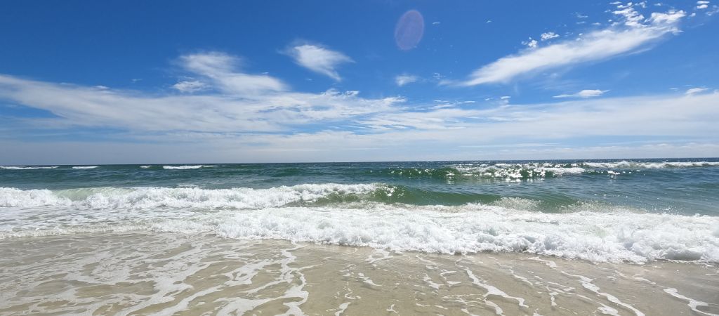 A sunny day at the beach with crashing waves.