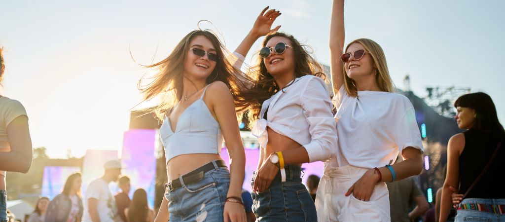 Three young girls excited with hands in the air at an outdoor event in Destin.