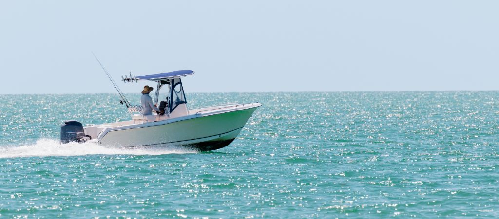 A person driving a boat with fishing rods on the Emerald Coast.