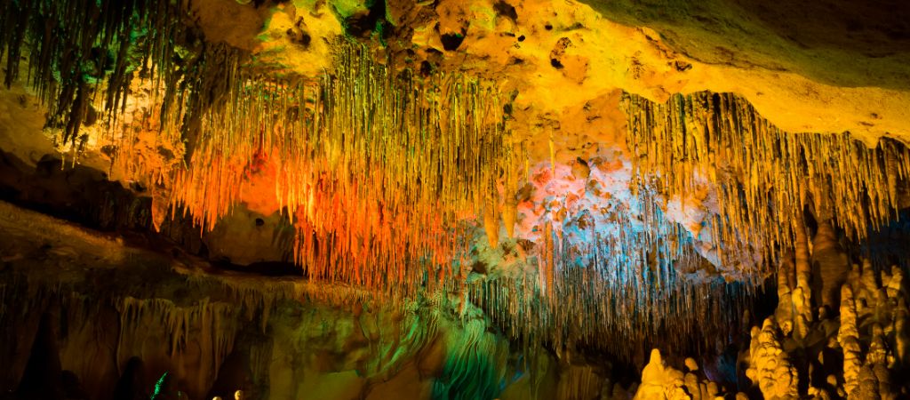 Colorful lights illuminate a large cave filled with stalactites at Florida Caverns State Park.