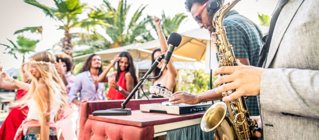 Jazz band plays while a group of young people dance among palm trees.